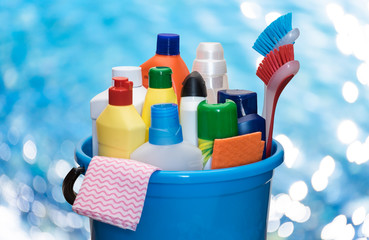 Set of detergents  in bottles with brush and napkins in a bucket.