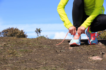 Fototapeta na wymiar young woman trail runner tying shoelace on mountain peak