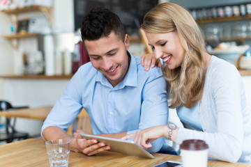 Couple using digital tablet in cafe
