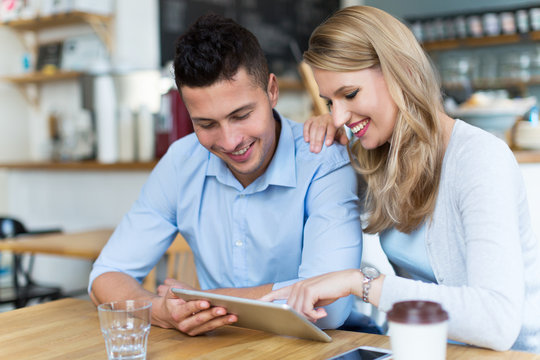 Couple using digital tablet in cafe

