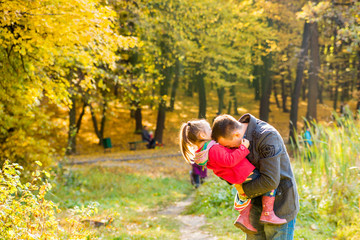 Father and daughter playing outdoors in the park in th sunny autumn day. 