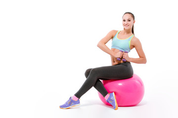 Young sportswoman exercising with dumbbells sitting on fitball