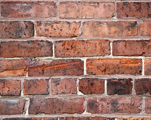 Close up of textured wall of red bricks and cement
