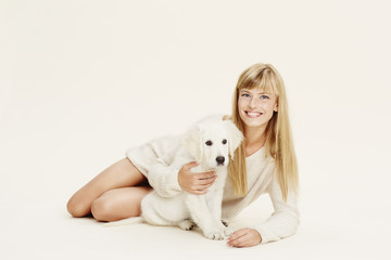 Blond woman and puppy lying in studio