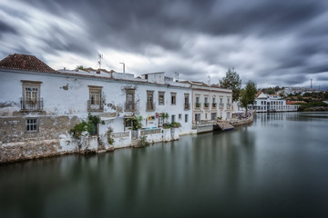 Obraz premium A dramatic urban landscape of ancient houses on the river. Tavira, Portugal.