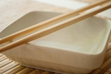 Fototapeta na wymiar bol et baguettes chinoises sur set de table en bambou