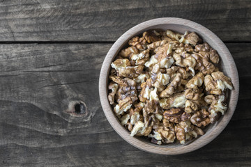 Walnuts in wooden bowl on wooden table