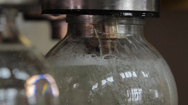 Jar filling up to end and turning around in pouring mechanism at a factory