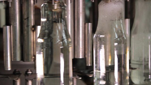 Glass bottles move on conveyor and filling by liquid