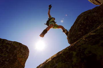 man jumping cliff with blue sky