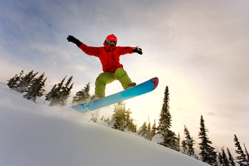 Snowboarder doing a toe side carve with deep blue sky in backgro