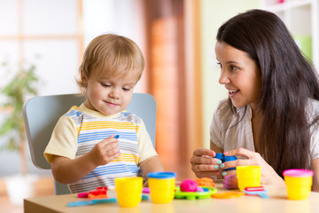 child boy and woman play colorful clay toy at nursery or