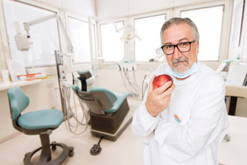 Obraz premium Senior dentist at her office with a apple