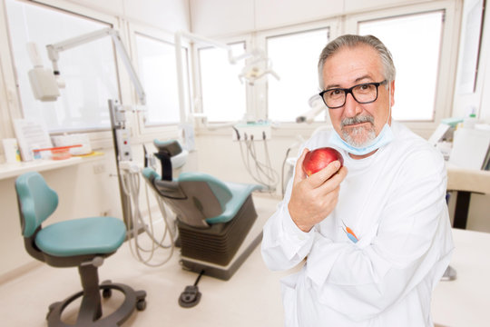 Senior dentist at her office with a apple