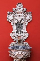 Ornamented faucet on the red wall 