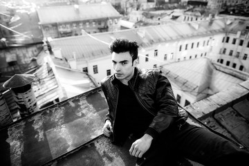 Man in a leather jacket on a rooftop in the center of the city