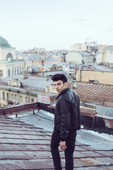 Man in a leather jacket on a rooftop in the center of the city