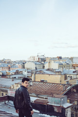 Man in a leather jacket on a rooftop in the center of the city