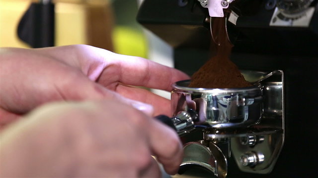 Barista pours coffee in the portafilter espresso machine. Close up.