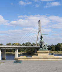 Warsaw mermaid (Syrenka) statue with Holy cross Bridge (Swietokrzyski) in background. Symbol/emblem of Warsaw. Statue made of gunmetal, was erected in April 1939.