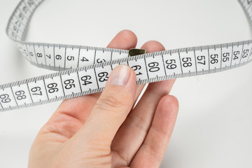 Hand holding measuring tape on a white background