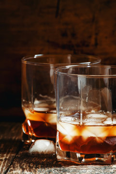 Two glasses of whiskey with ice, dark toned image, selective foc