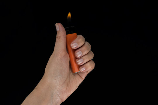 Burning lighter in female hand, isolated on black