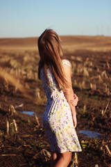Obraz premium Beauty Romantic Girl Outdoors. Beautiful Teenage Model girl Dressed in Casual Dress on the Field in Sun Light. Blowing Long Hair. Autumn. Glow Sun, Sunshine. Toned in warm colors