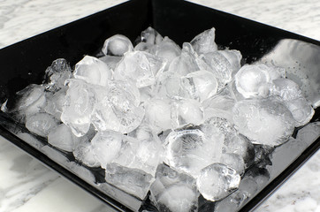 Many of ice cubes on a black plate