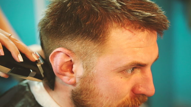 Barber cuts the hair of the client with clipper.