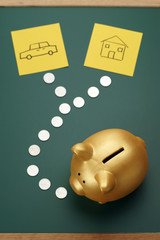 House and car savings - golden piggy bank, coins and house and c