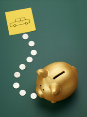 Dream car savings - golden piggy bank, coins and a car on blackb
