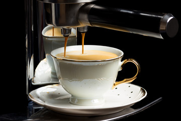 Coffee machine pouring a cup of espresso on black background.