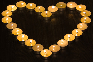 tea candles in the shape of a heart on wood background