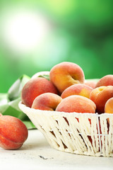 Ripe peaches fruit in basket on a white wooden background