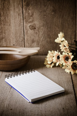 Open cookbook and kitchenware on wooden background