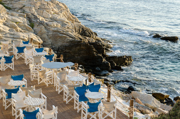 Empty seaside terrace. White wooden chairs and tables. Spectacular view