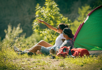 Couple camping. Young people sitting in tent and looking over the landscape.