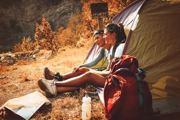 Zelfklevend Fotobehang Paar kamperen. Jong koppel in tent zitten en ontspannen. © BalanceFormCreative