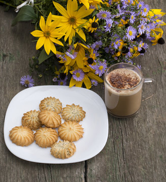 plate with cookies, a cappuccino and wild flowers, on an old tab