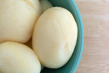 White potatoes in a bowl on a wood table top