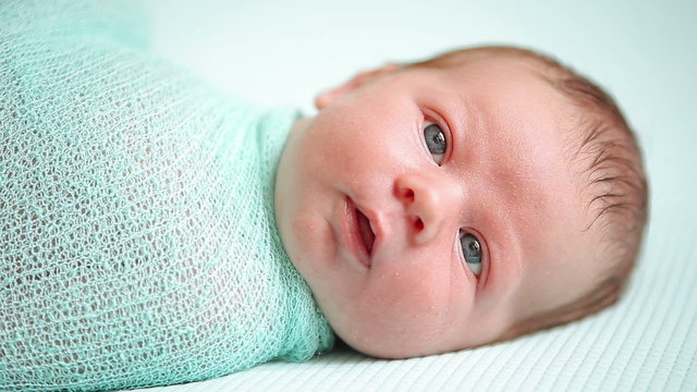 Adorable blue-eyed newborn baby lying and looking around in