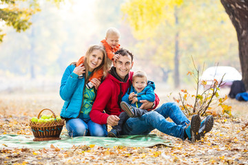 Happy young family with two boys in autumn forest