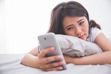 Woman using cellphone on the bed