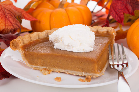 Slice of Pumpkin Pie With Autumn Decor in Background