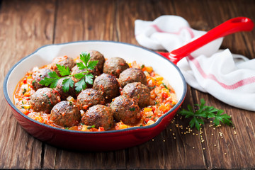Meatballs with vegetable sauce in cast iron skillet on wooden background, selective focus