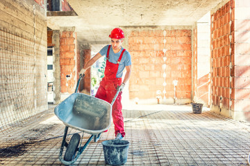 worker with empty wheelbarrow on construction site