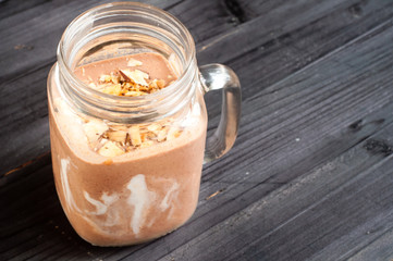 Healthy chocolate flavor smoothie milkshake made from blended cacau,chia with yoghurt swirl. Served in a jug style glass with nut topping.
