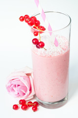 Mixed berry smoothie milkshake made from blended red berries and strawberries with yogurt. Sprinkled with coconut and served in a glass with a pink rose and isolated on a white background.