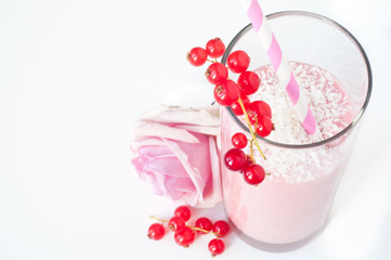 Mixed berry smoothie milkshake made from blended redberries and strawberries with yogurt. Sprinkled with coconut and served in a glass with a pink rose and isolated on a white background.